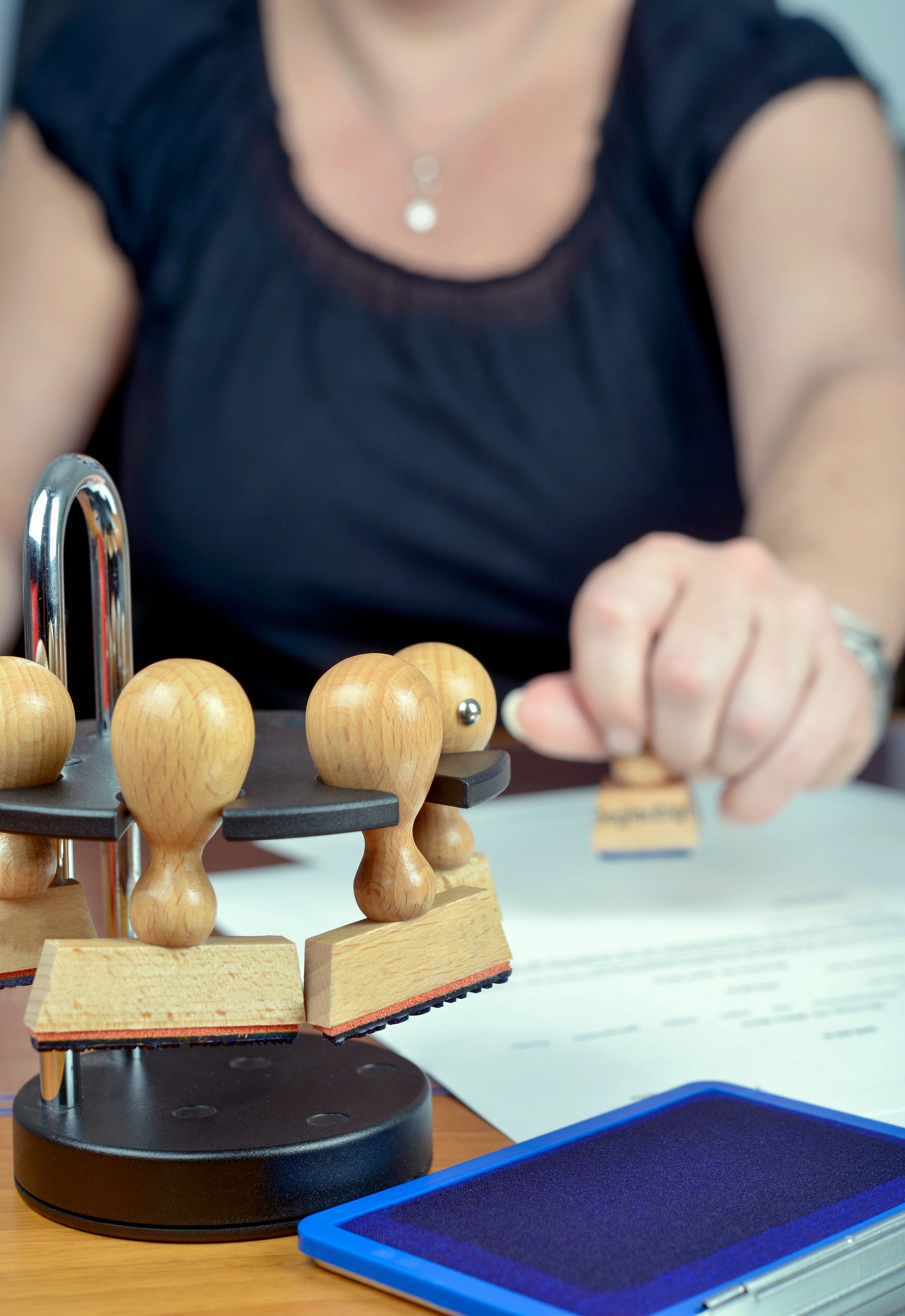 Office and paperwork: Female clerk is doing certifications with a stamp, selective focus